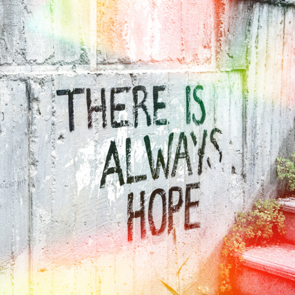 pragmental-splash-sq-newe Photo of the words "There is always hope" painted on a cement wall with a rainbow of light around it